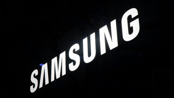 The image features the illuminated logo of Samsung, prominently displayed against a dark background. The logo is captured in a way that emphasizes its modern and sleek design.
