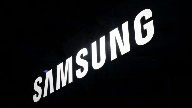 The image features the illuminated logo of Samsung, prominently displayed against a dark background. The logo is captured in a way that emphasizes its modern and sleek design.