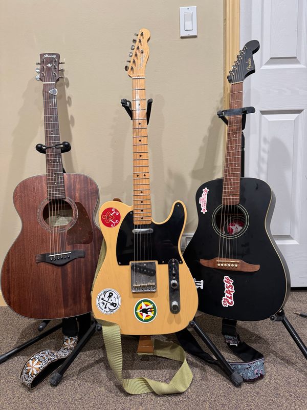Three guitars - an Ibanez Artwood acoustic, a Fender Telecaster, and a Fender Joe Strummer Edition Campfire acoustic - on stands in my office.