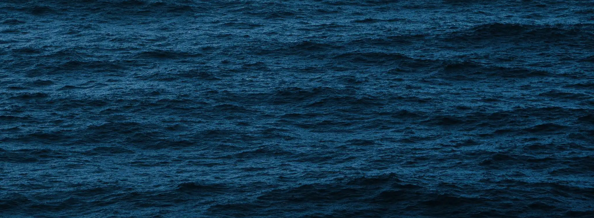 A vast expanse of deep dark blue ocean waves, reflecting the depth and tranquility of the natural world.