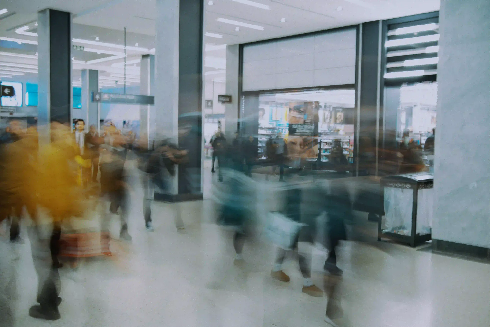 Blurred silhouettes of passengers rushing through a brightly lit, sterile airport terminal, illustrating the exhaustion of modern air travel.