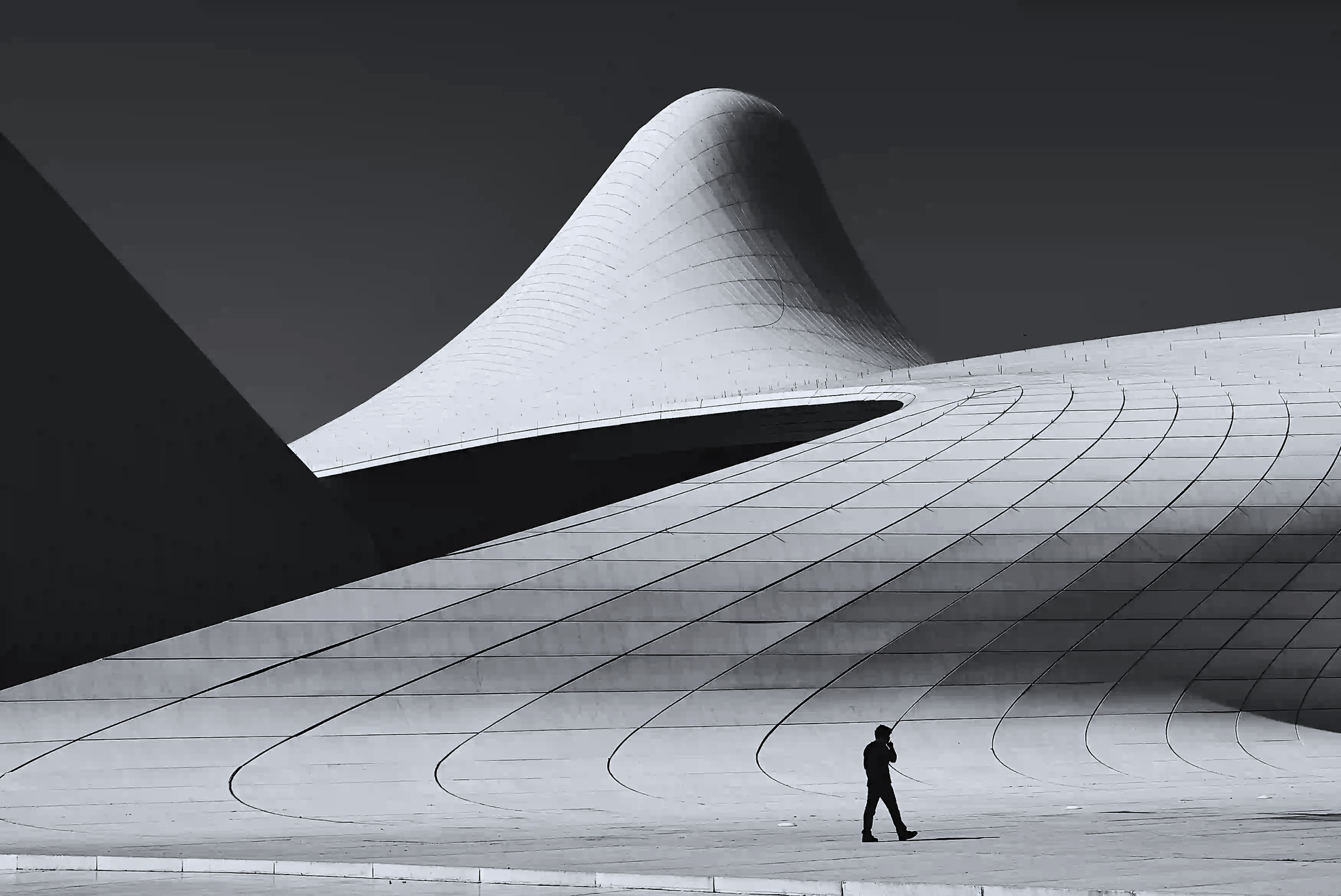A tiny human silhouette walking in front of massive architecture, representing the small scale of individual impact compared to global systems.