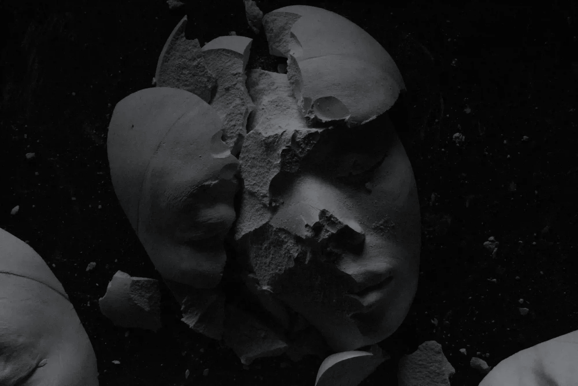 A shattered white stone face with closed eyes resting in darkness, symbolizing the fragmented city-states of 19th-century Italy.