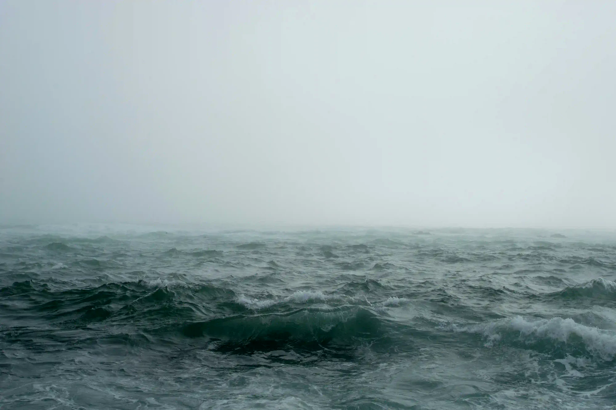 A turbulent, dark ocean surface enveloped in thick fog, representing the vast and unforgiving waters of the North Pacific.