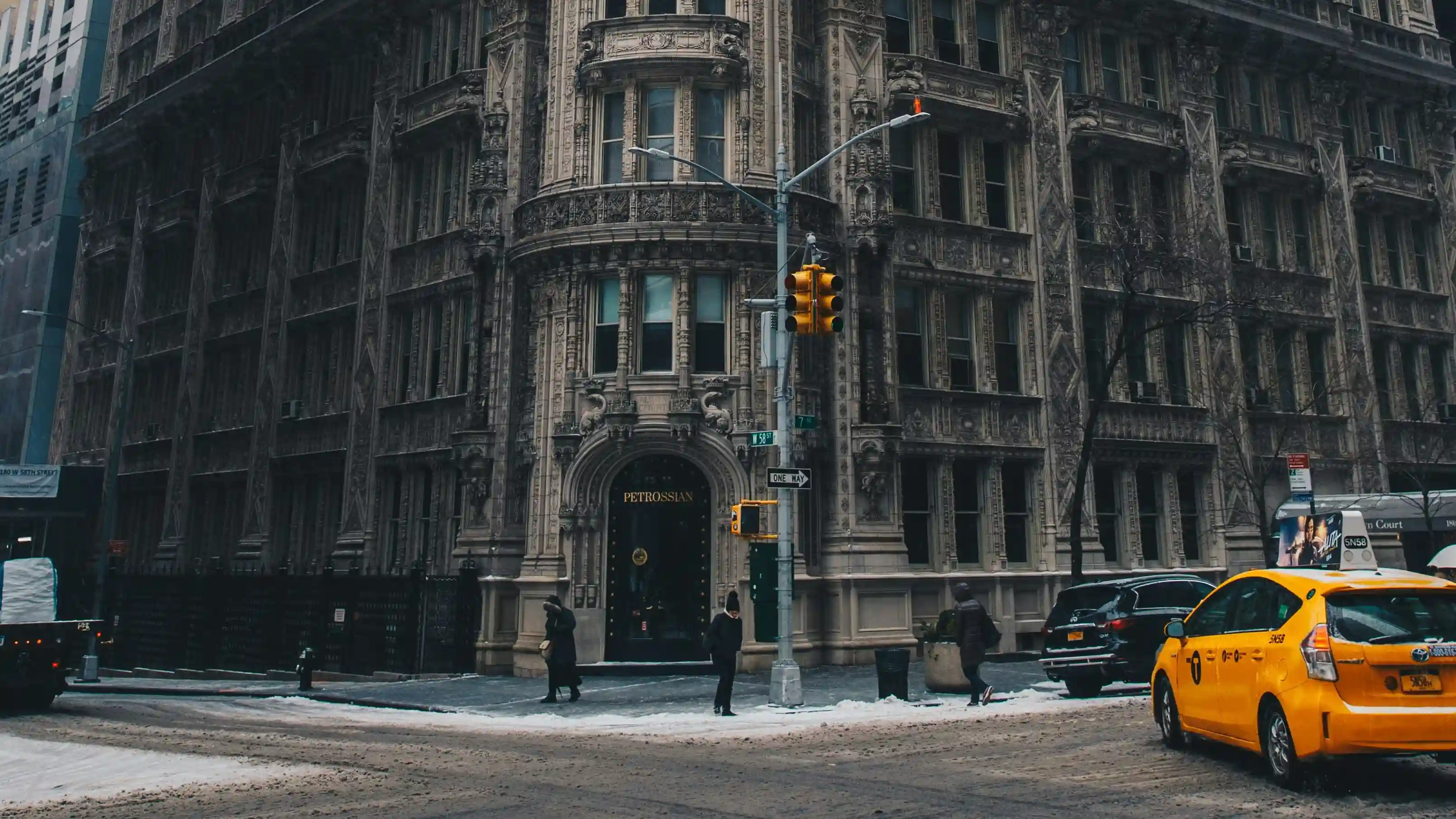Historic ornate New York building standing against modern glass skyscrapers during a snowy winter day, illustrating urban complexity and the sidewalk ballet.