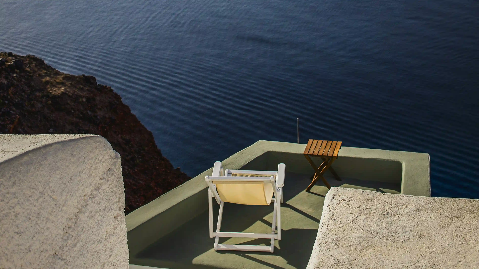 An empty chair on a sunlit terrace overlooking the deep blue sea, symbolizing the ancient Roman concept of otium and the art of doing nothing.