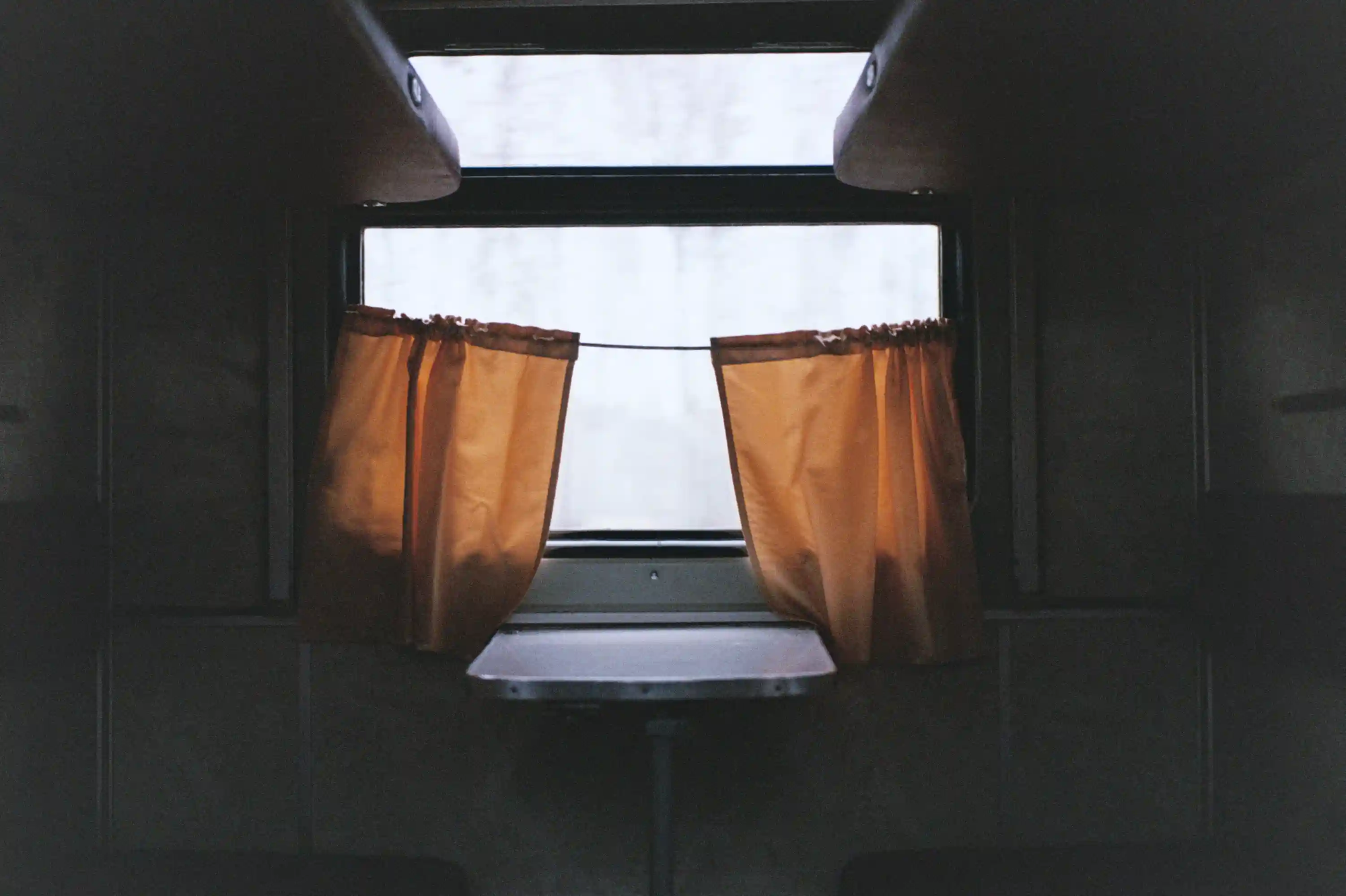 The interior of a private train compartment with a small table and curtains, representing the comfort of overnight train travel.