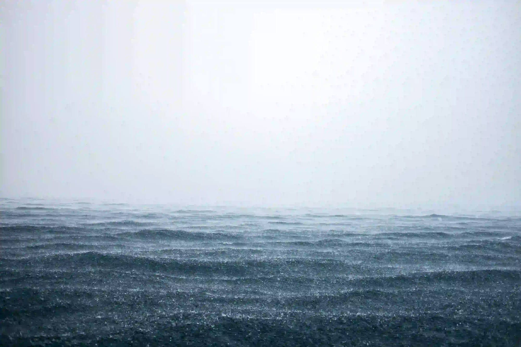 A vast, choppy dark ocean surface blending into a thick, misty grey fog with no visible horizon.