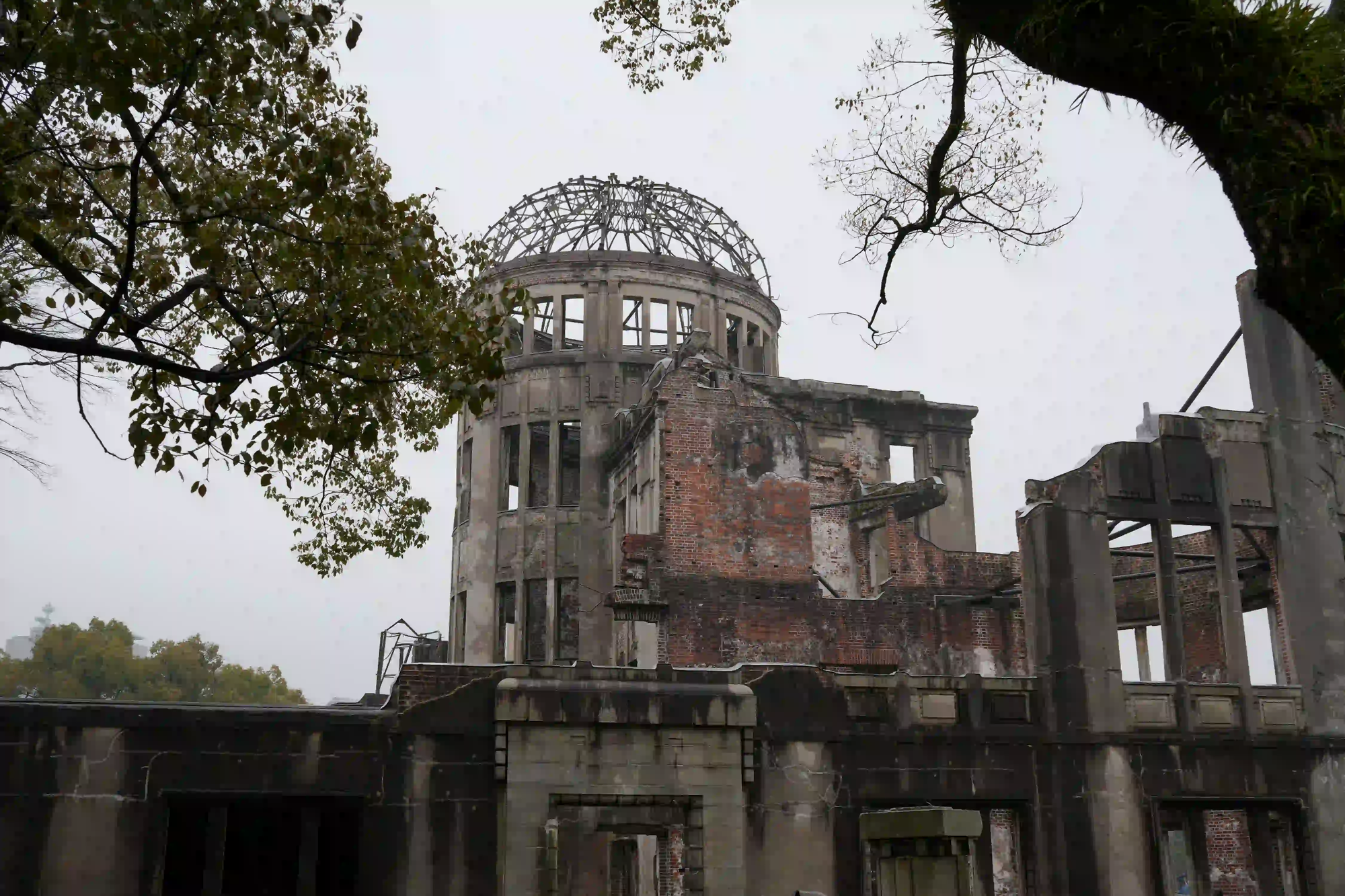 The skeletal ruins of the Genbaku Dome in Hiroshima, standing under an overcast sky as a somber reminder of nuclear devastation.