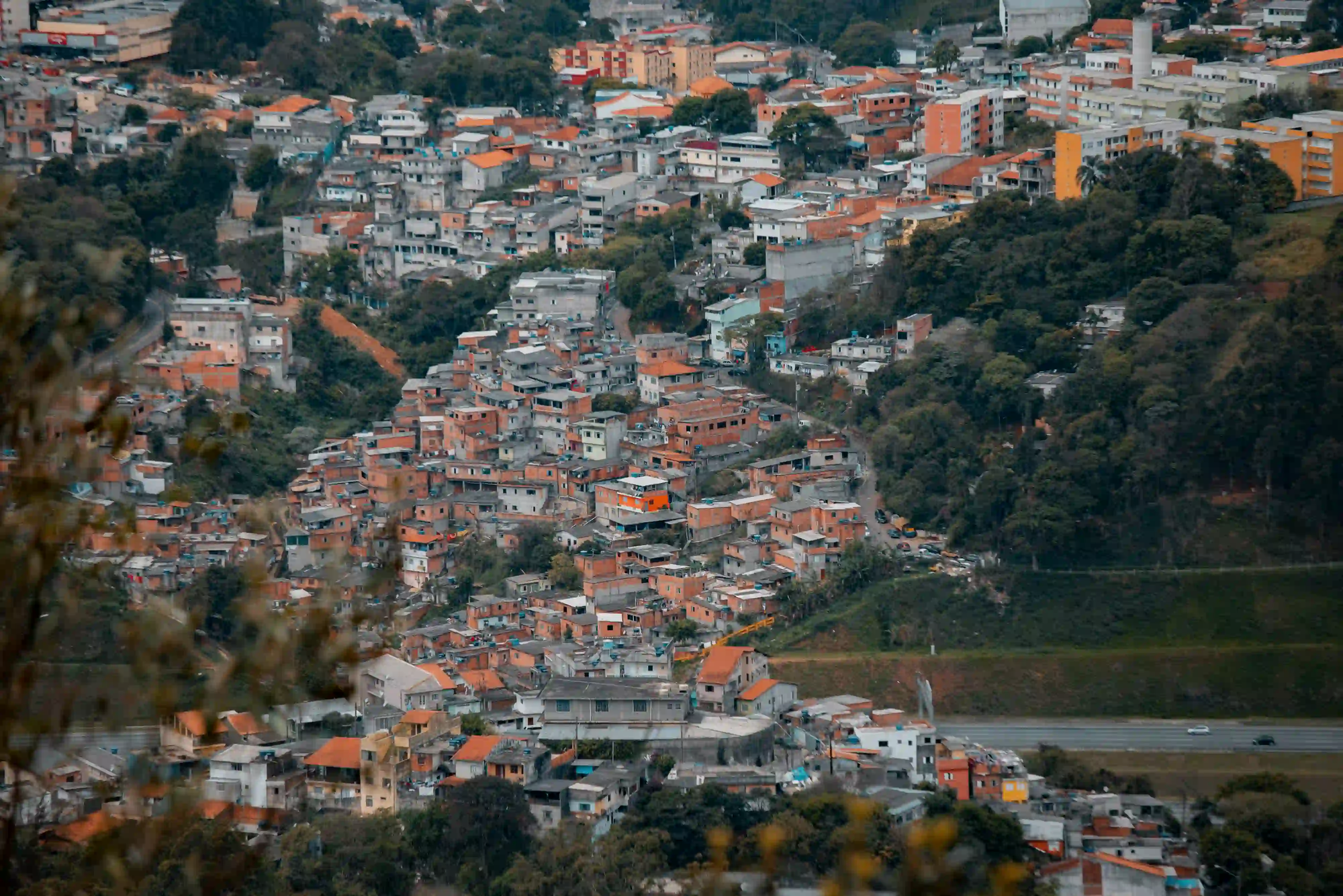 A sprawling hillside favela in São Paulo with densely packed brick houses, revealing the stark sociological reality once hidden behind the city's advertising billboards.