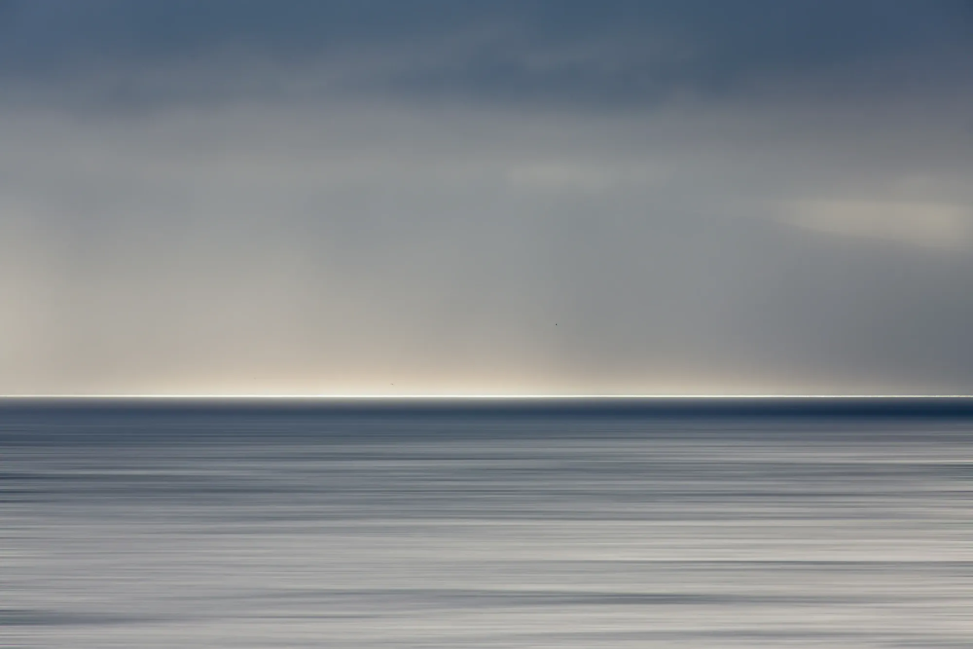 An abstract, heavily blurred view of a vast and moody horizon line, representing the immense distances covered by the 3,500-kilometer Seven Sisters Songline.