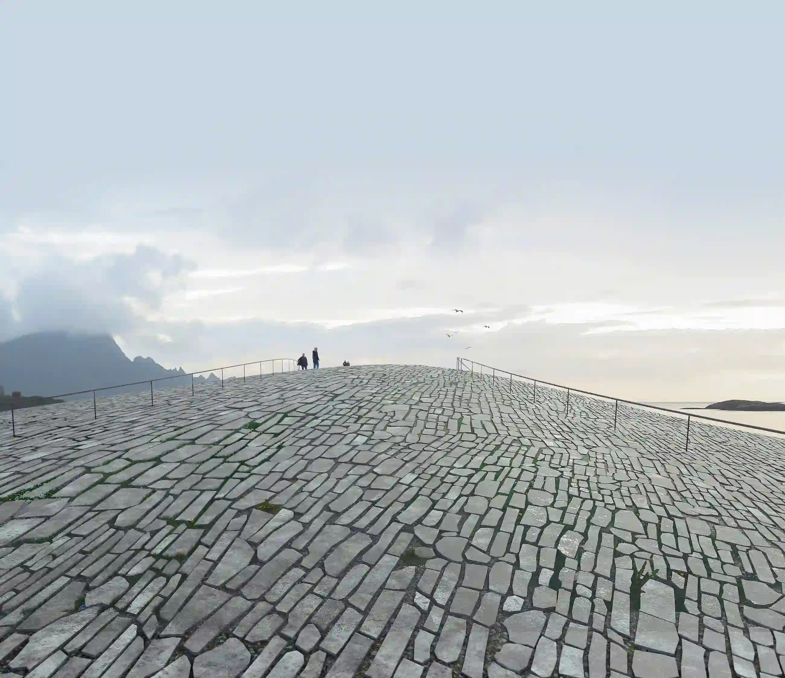 A minimalist view of people walking on the curved, stone-clad roof of The Whale museum, which seamlessly mimics the natural Norwegian bedrock.