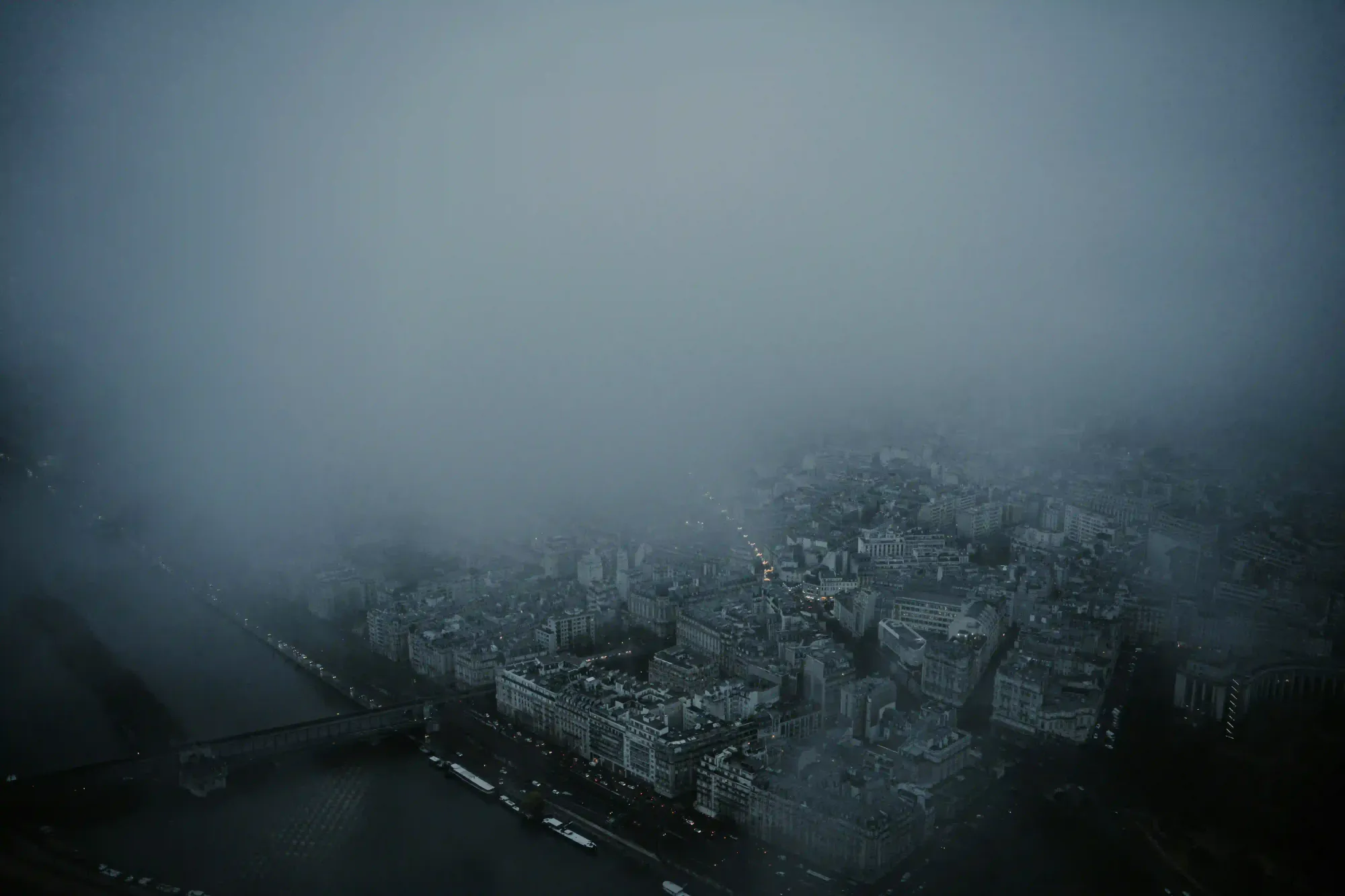 Aerial view of a dense city landscape completely obscured by heavy, moody fog.