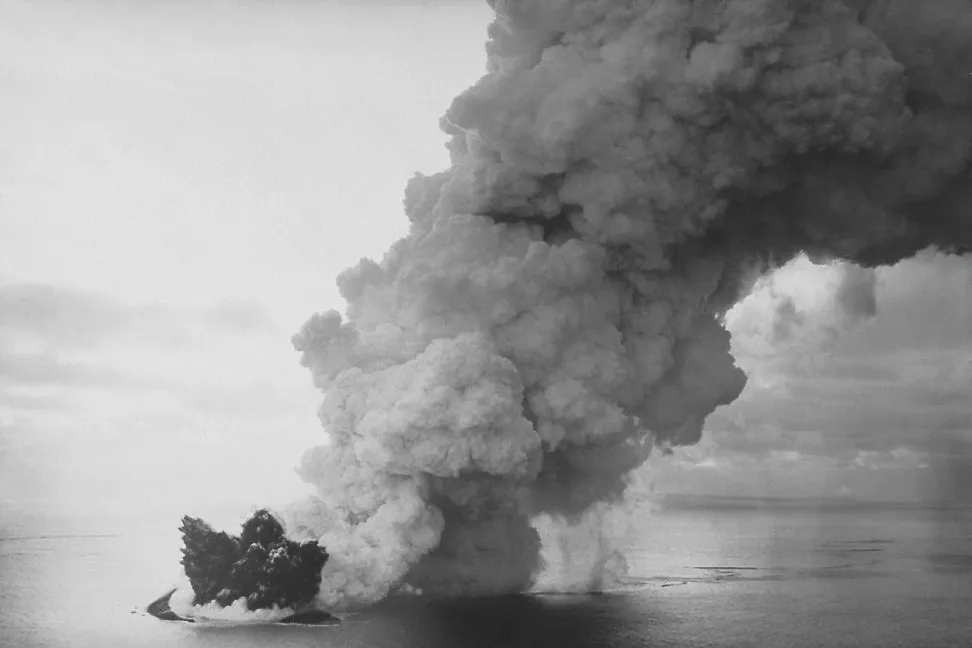 A massive, towering column of black volcanic ash erupting from the ocean, showing the violent creation of Surtsey island.