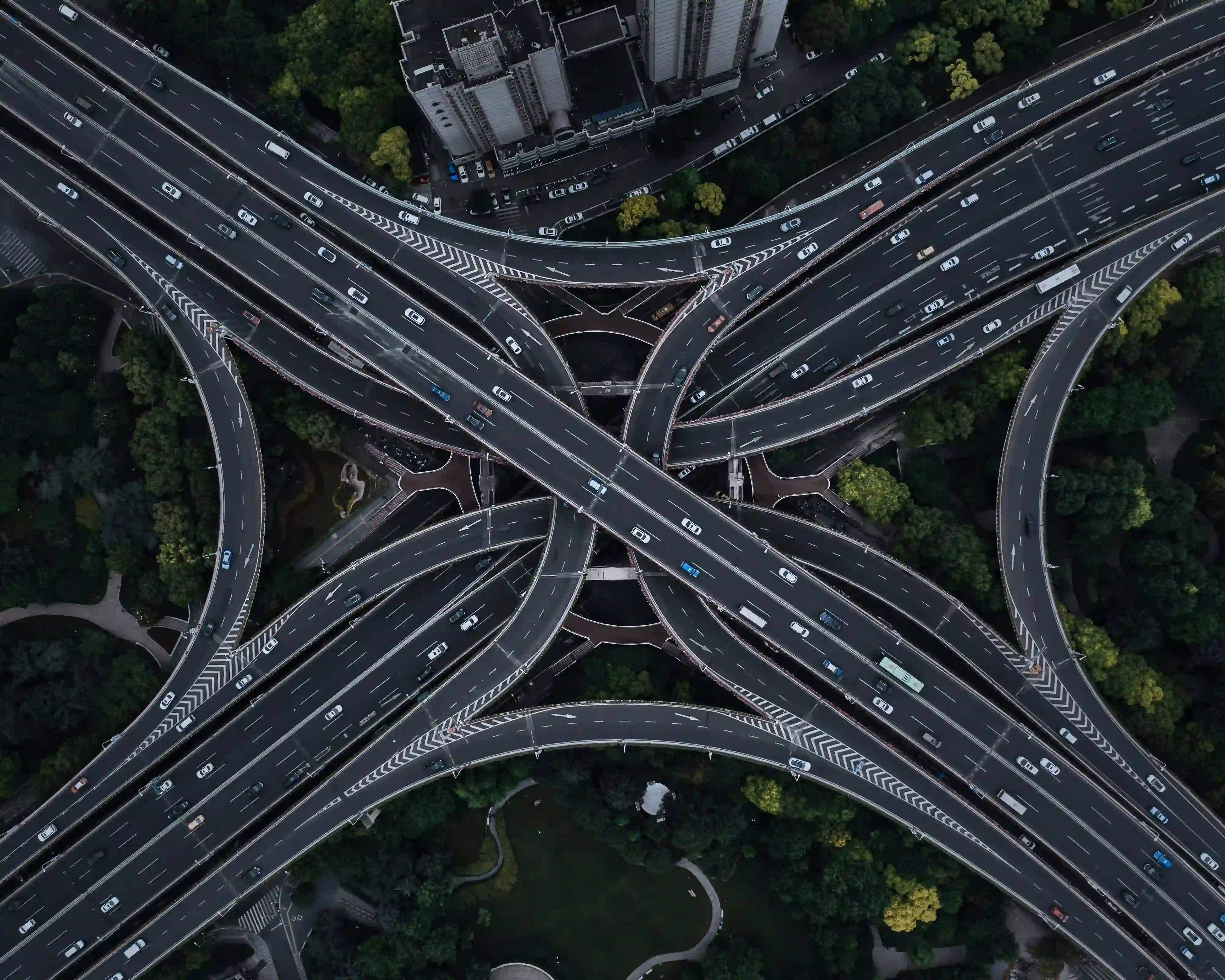 Top-down aerial view of a massive, intertwined highway interchange dominating the urban landscape.