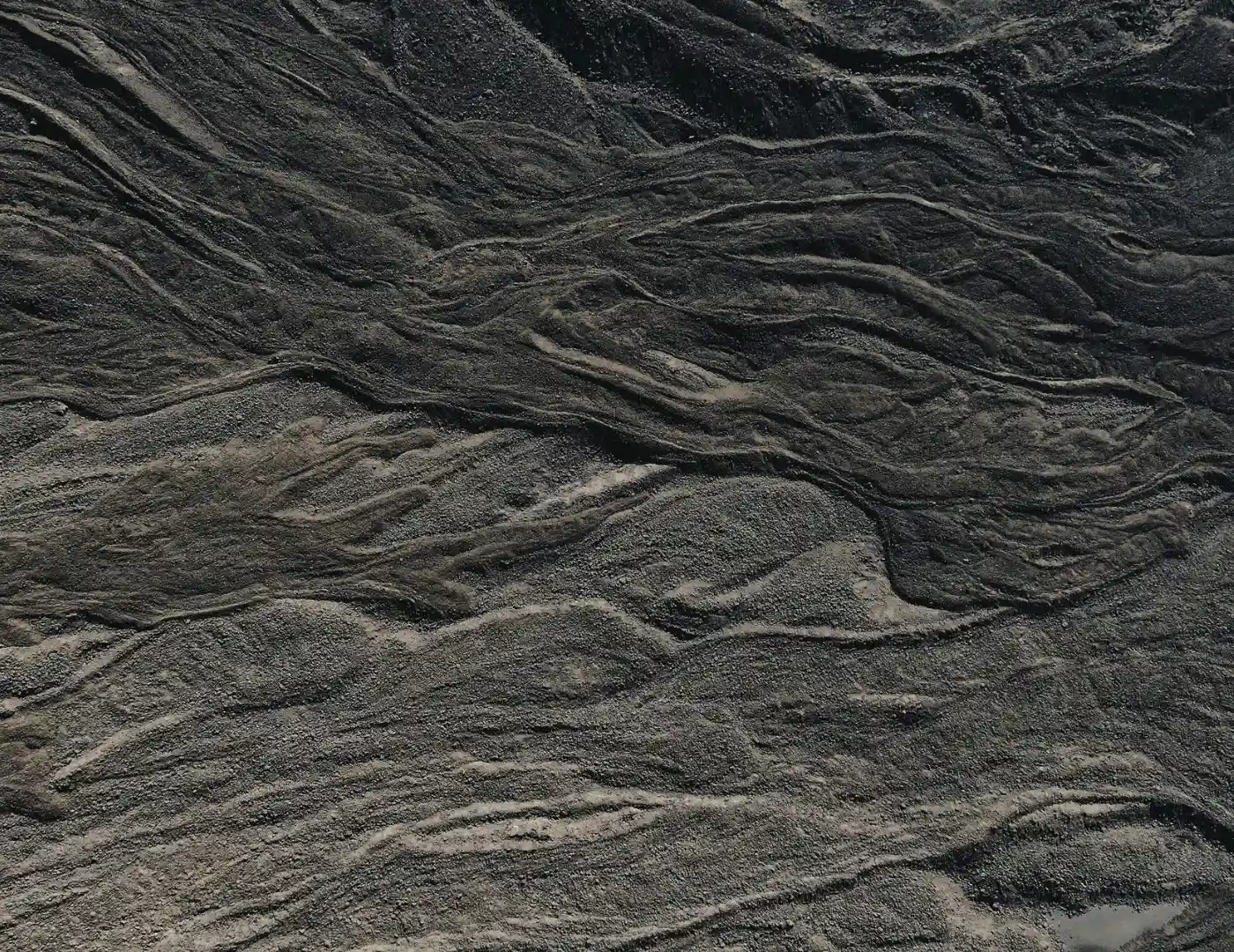 Dark, flowing geological layers resembling organic tissue or brain folds, representing the historical accumulation of the human mind.