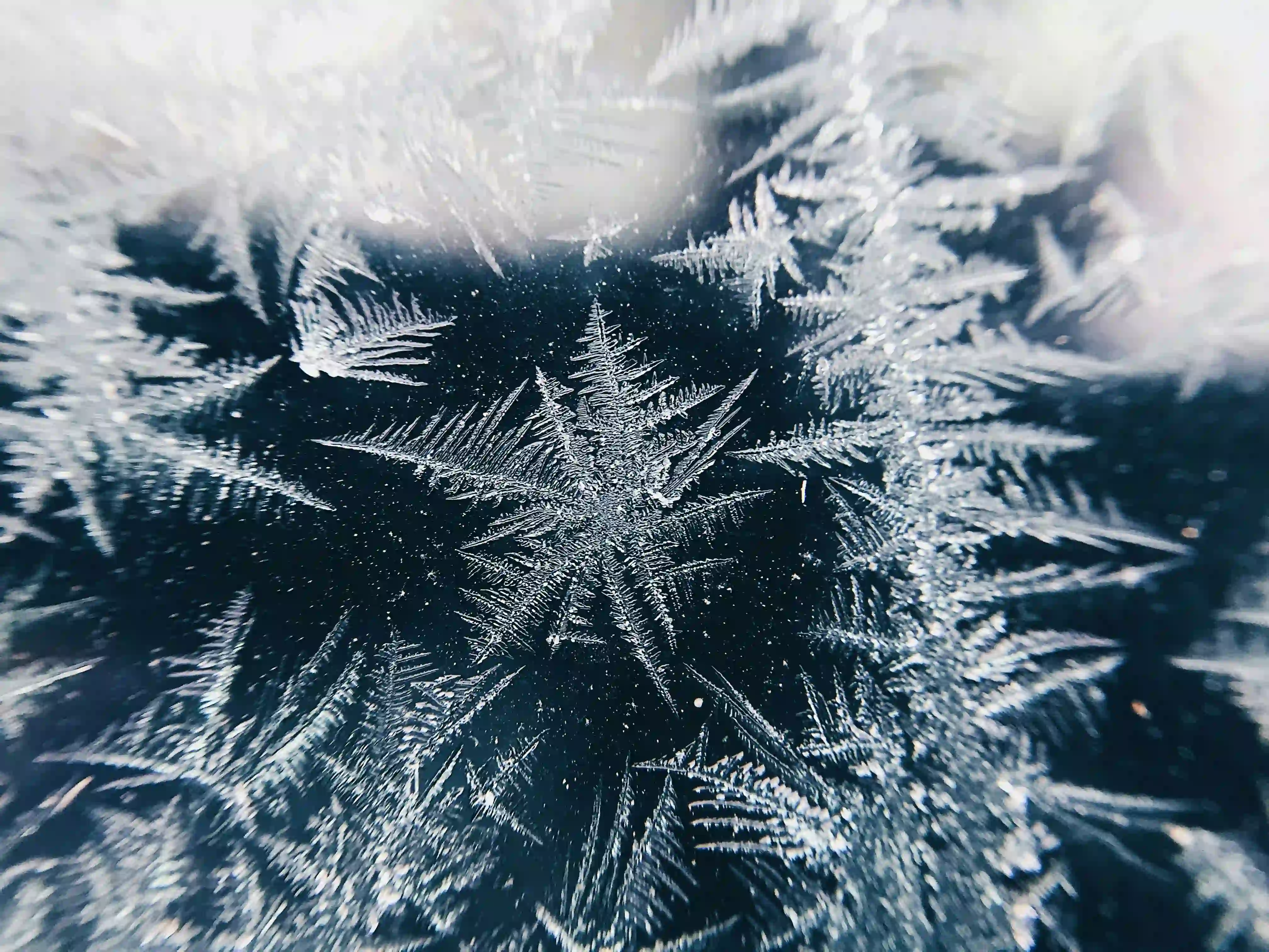 A macro photograph of a sharp, geometric ice crystal on a dark background, illustrating the molecular freezing process of weather modification.