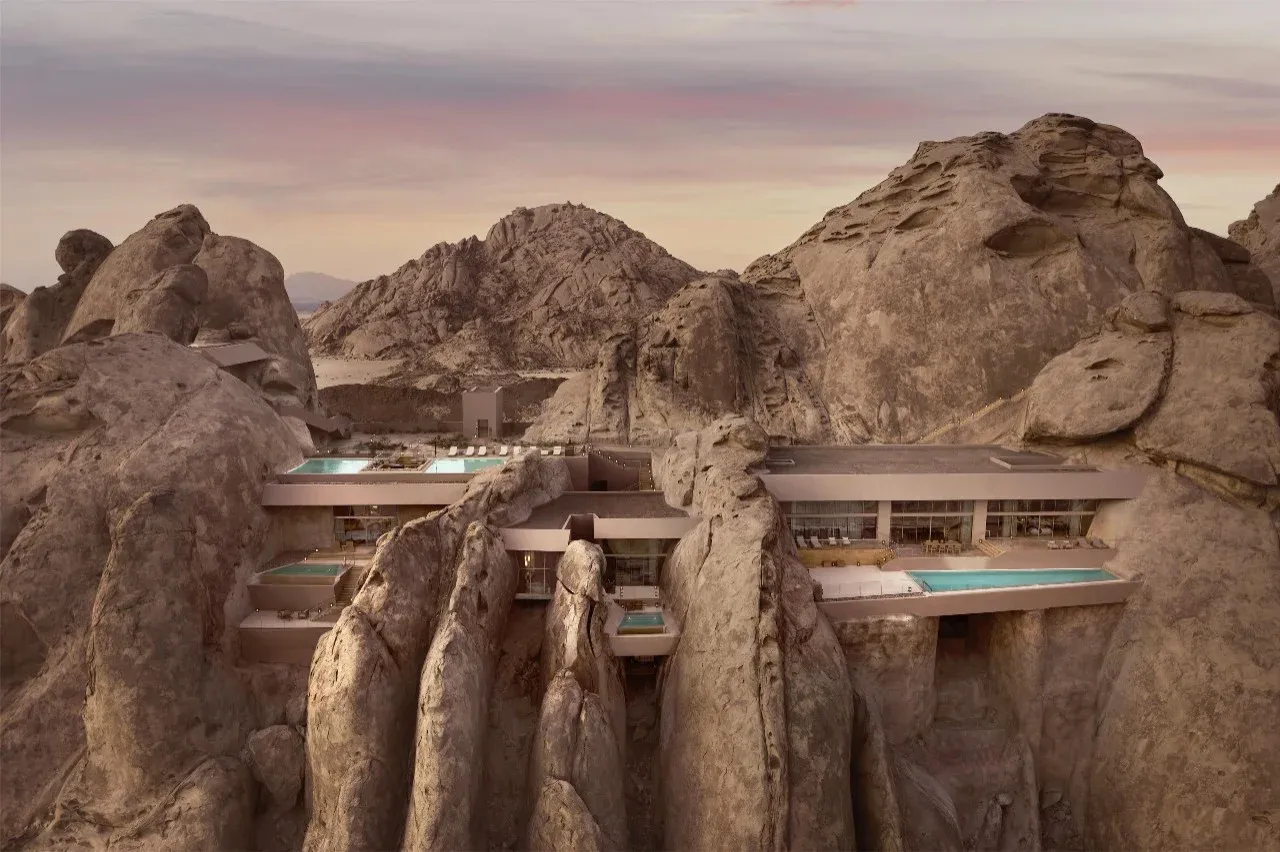 Aerial view of Desert Rock Resort carved directly into the granite mountains, showcasing rough luxury architecture.