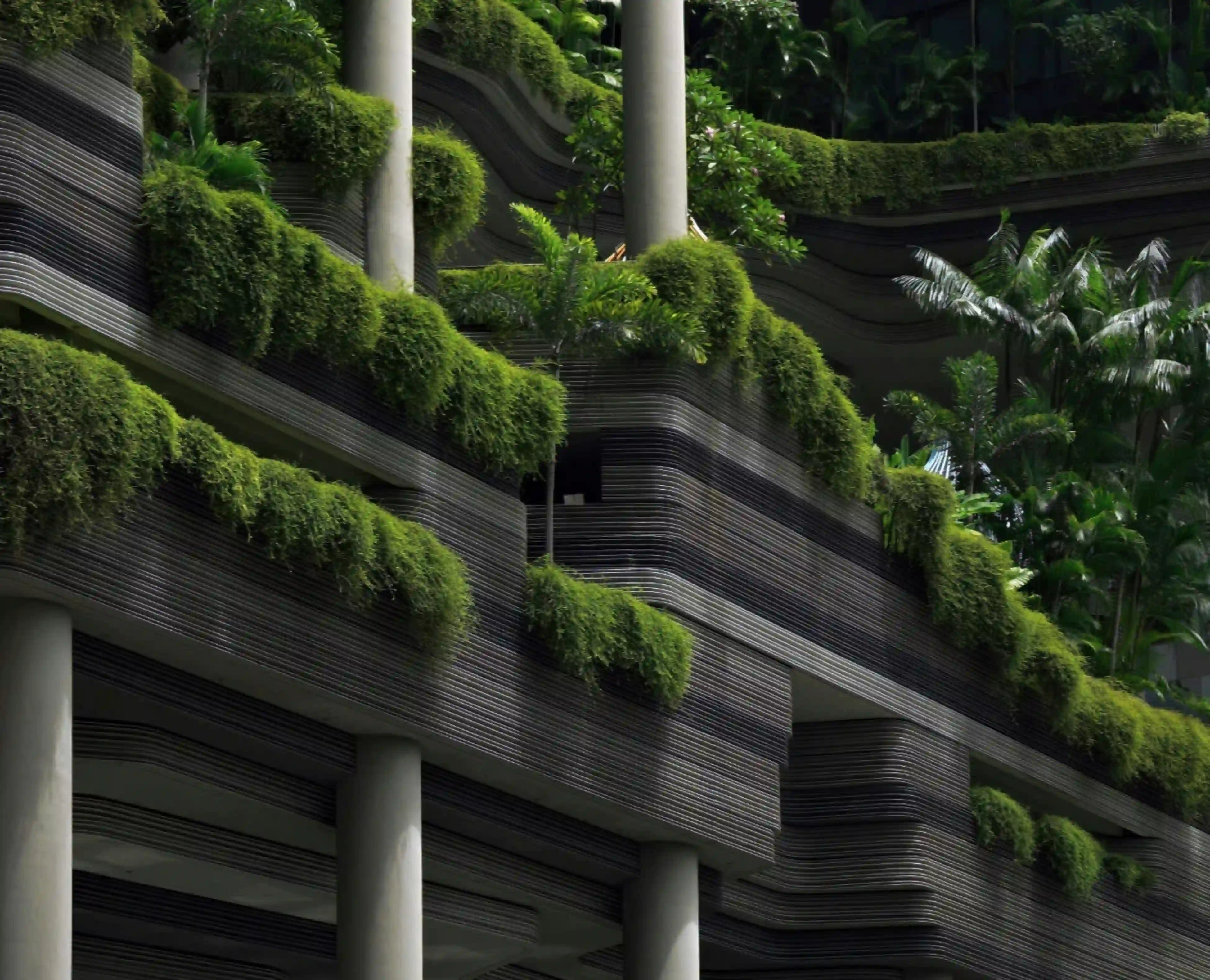 Architectural close-up of PARKROYAL COLLECTION Pickering in Singapore, showcasing curved concrete balconies layered with dense tropical foliage.