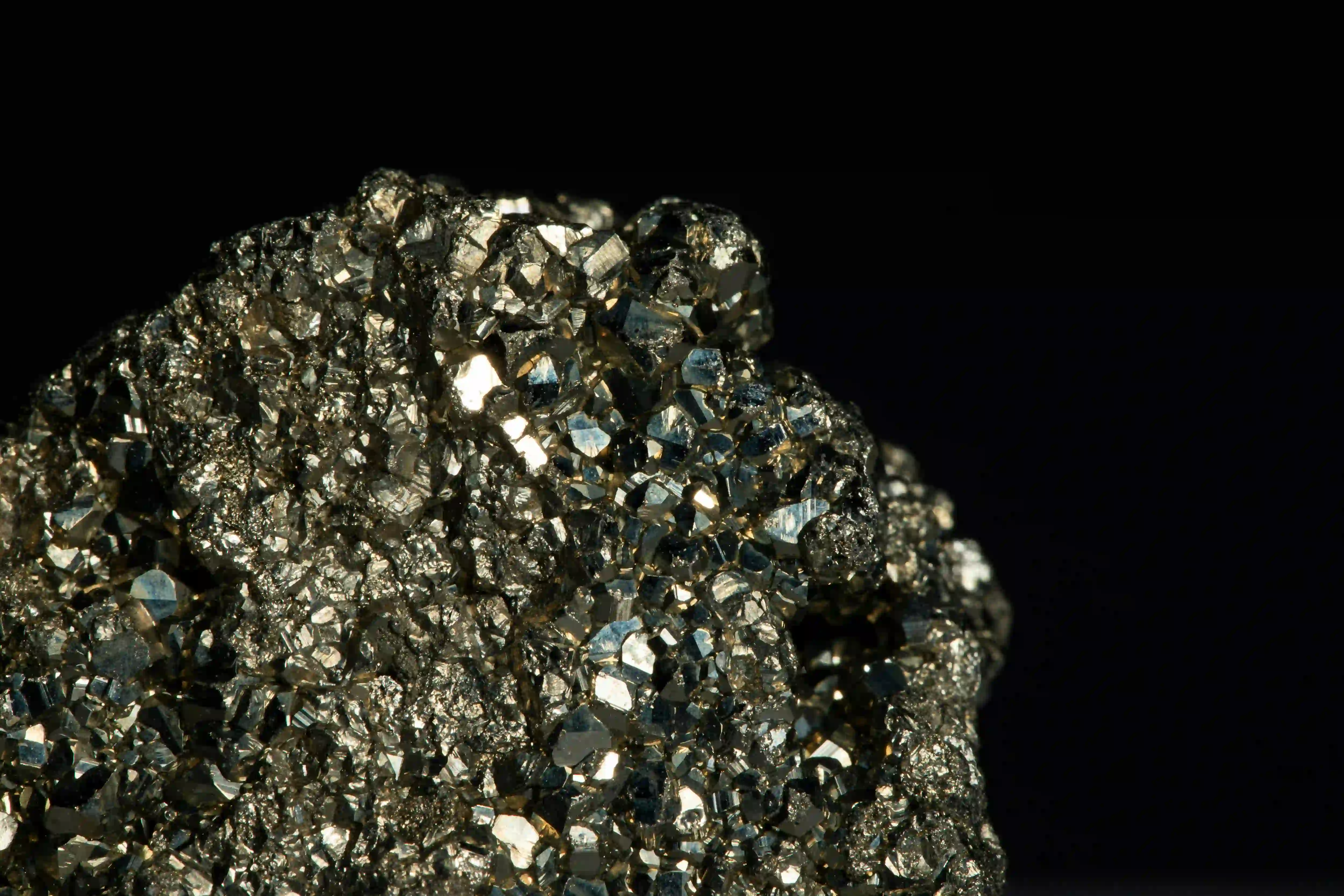 Macro shot of a complex metallic crystal structure emerging from a pure black background.