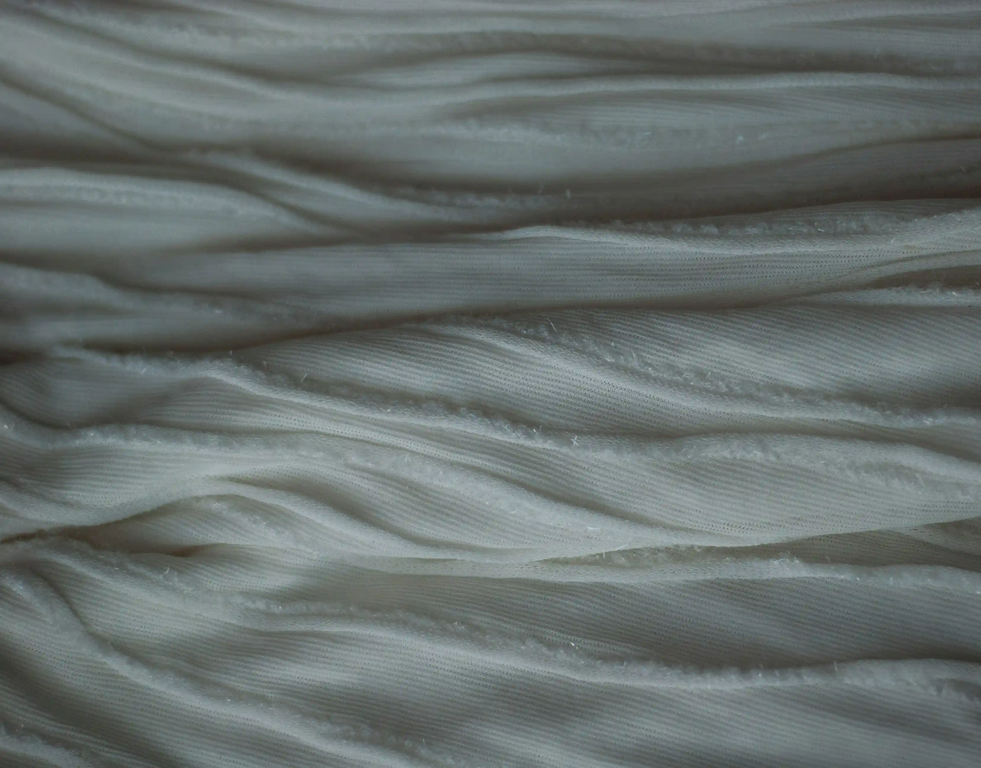 Close-up macro texture of cold gray synthetic fabric folds.
