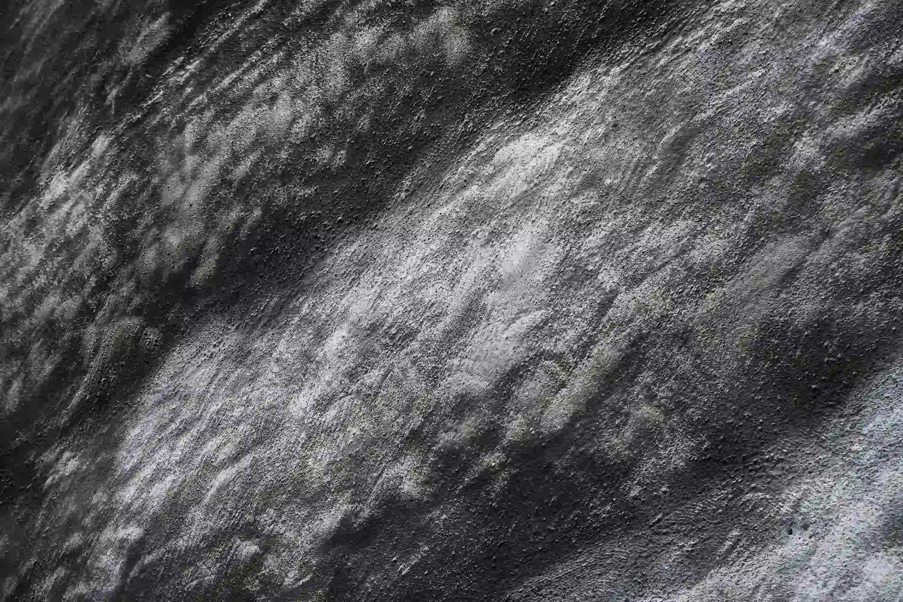 Close up texture of a dark weathered stone surface with diagonal organic patterns.