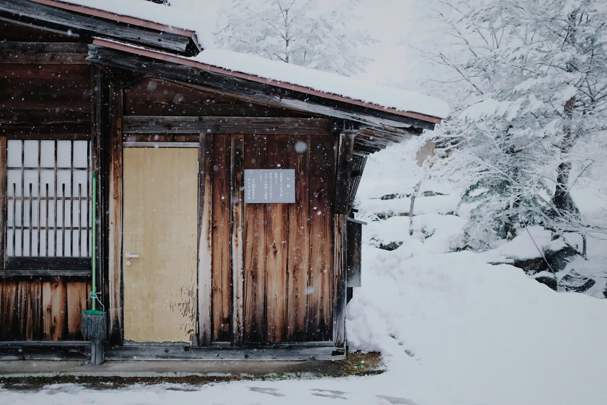 A traditional wooden Japanese house quietly standing in heavy winter snow, reflecting the isolation of rural Akiya homes.