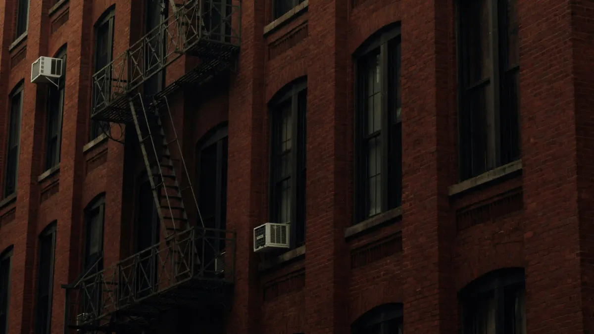 Historic red brick building with iron fire escapes in New York, representing the tangible urban memory against the flawless grid.