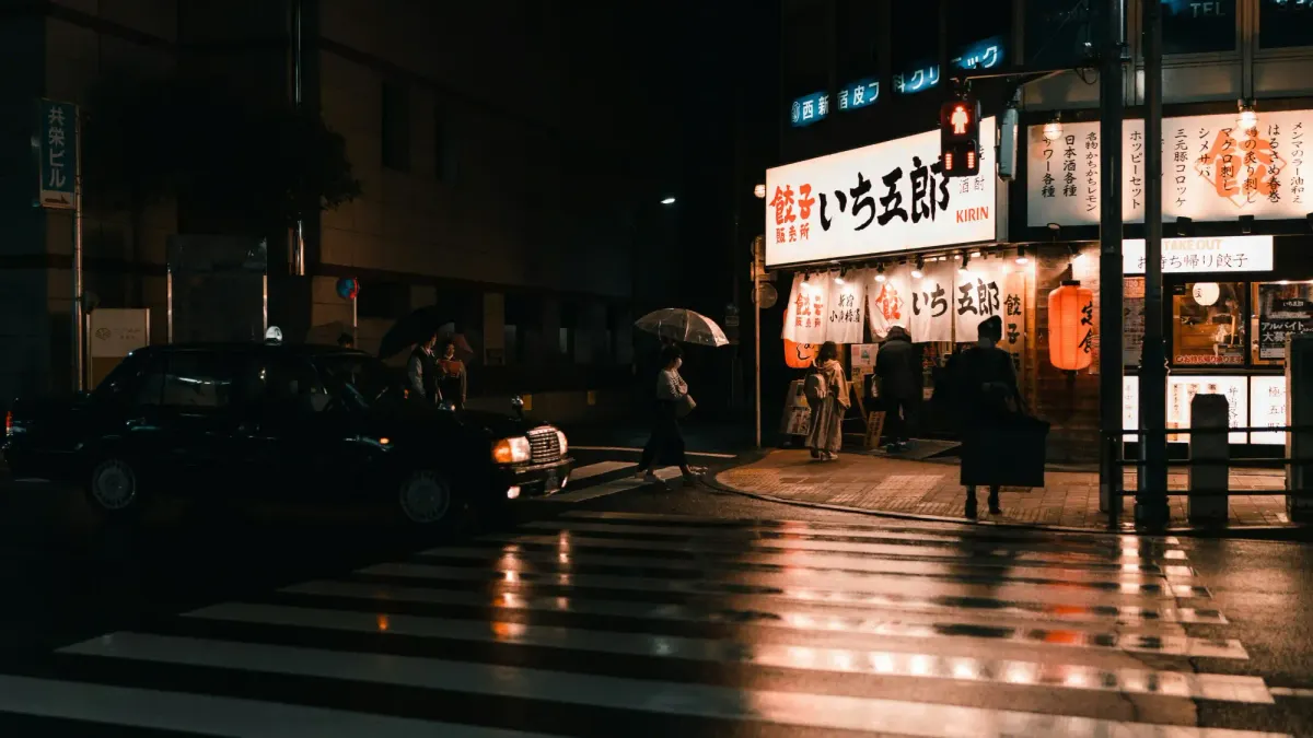 A cinematic rainy night in Tokyo, featuring a black taxi and a bright storefront, illustrating the aestheticization of everyday urban Japan.