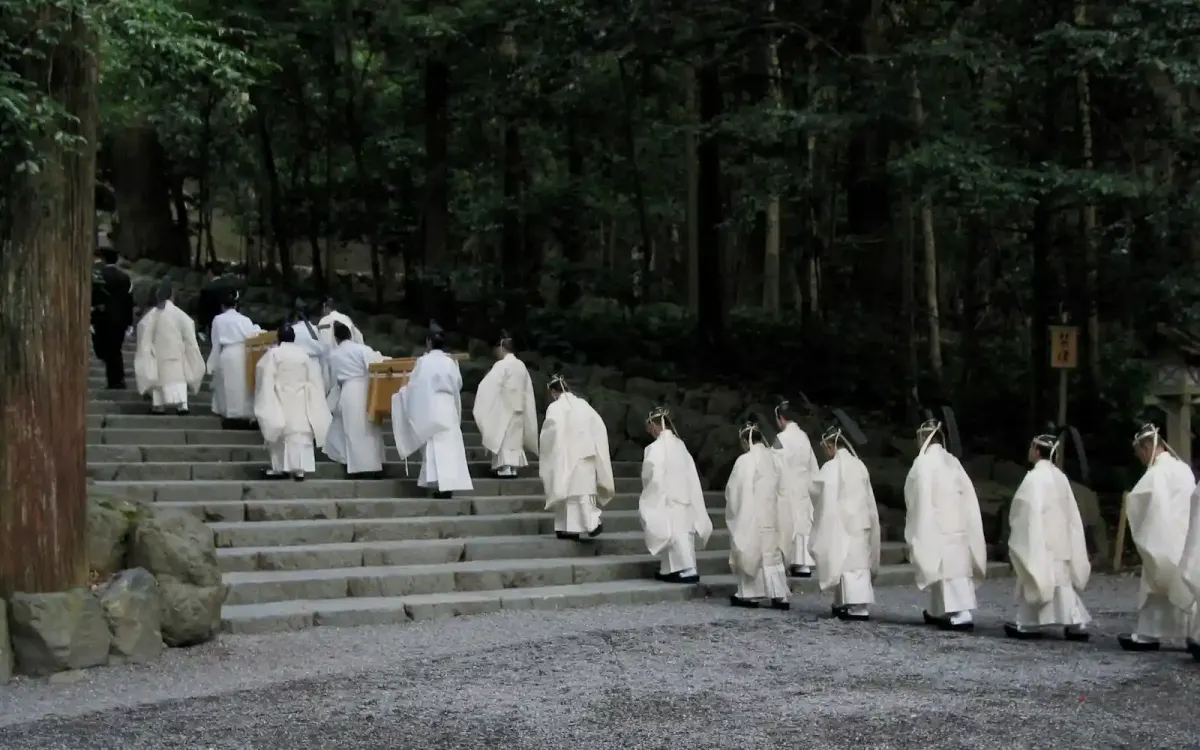 A solemn procession of Shinto priests in traditional white robes ascending the stone stairs within the ancient, dark forest of Ise Jingu.