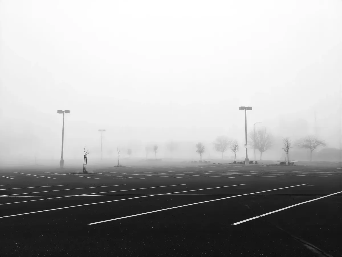 A desolate, fog-covered empty parking lot symbolizing the vast urban spaces surrendered to machines.