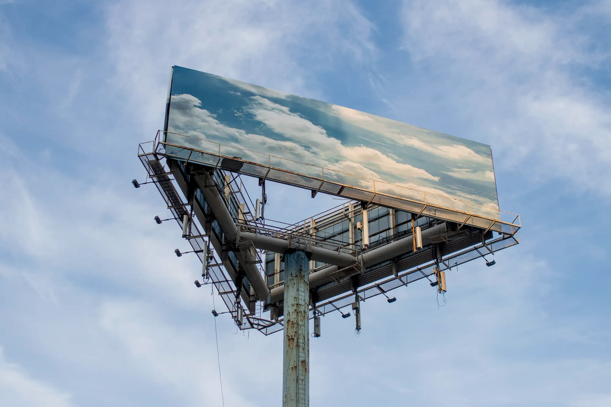 A heavy industrial billboard structure displaying a pristine blue sky, symbolizing the physical machinery behind digital cloud storage.