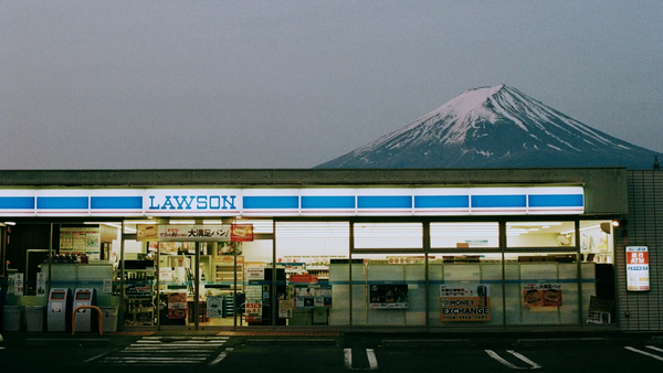 Mount Fuji looming over a brightly lit Lawson convenience store at dusk in Fujikawaguchiko, Japan, before the viral view was blocked.