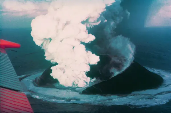 Aerial view from an airplane showing thick volcanic smoke rising from the newly formed Surtsey island.
