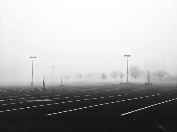 A desolate, fog-covered empty parking lot symbolizing the vast urban spaces surrendered to machines.