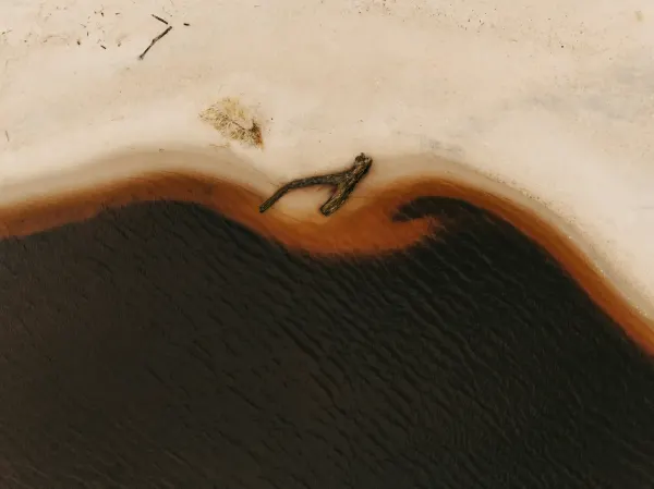Aerial view of a dark coastline and sand boundary representing the global sand crisis and stolen shores.