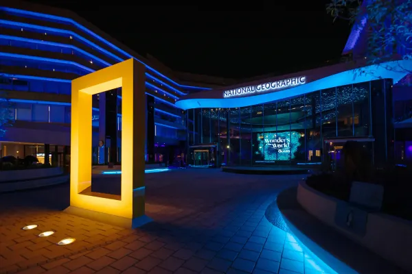 The illuminated iconic National Geographic yellow frame standing outside the new Museum of Exploration building at night.