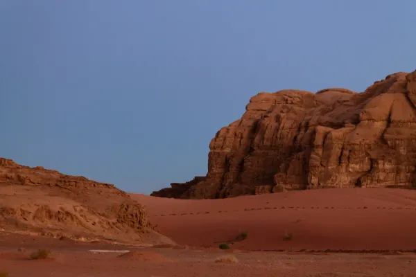 A massive red rock formation in a secluded desert at twilight, representing the rough luxury architecture of isolated Michelin 3-Key hotels.