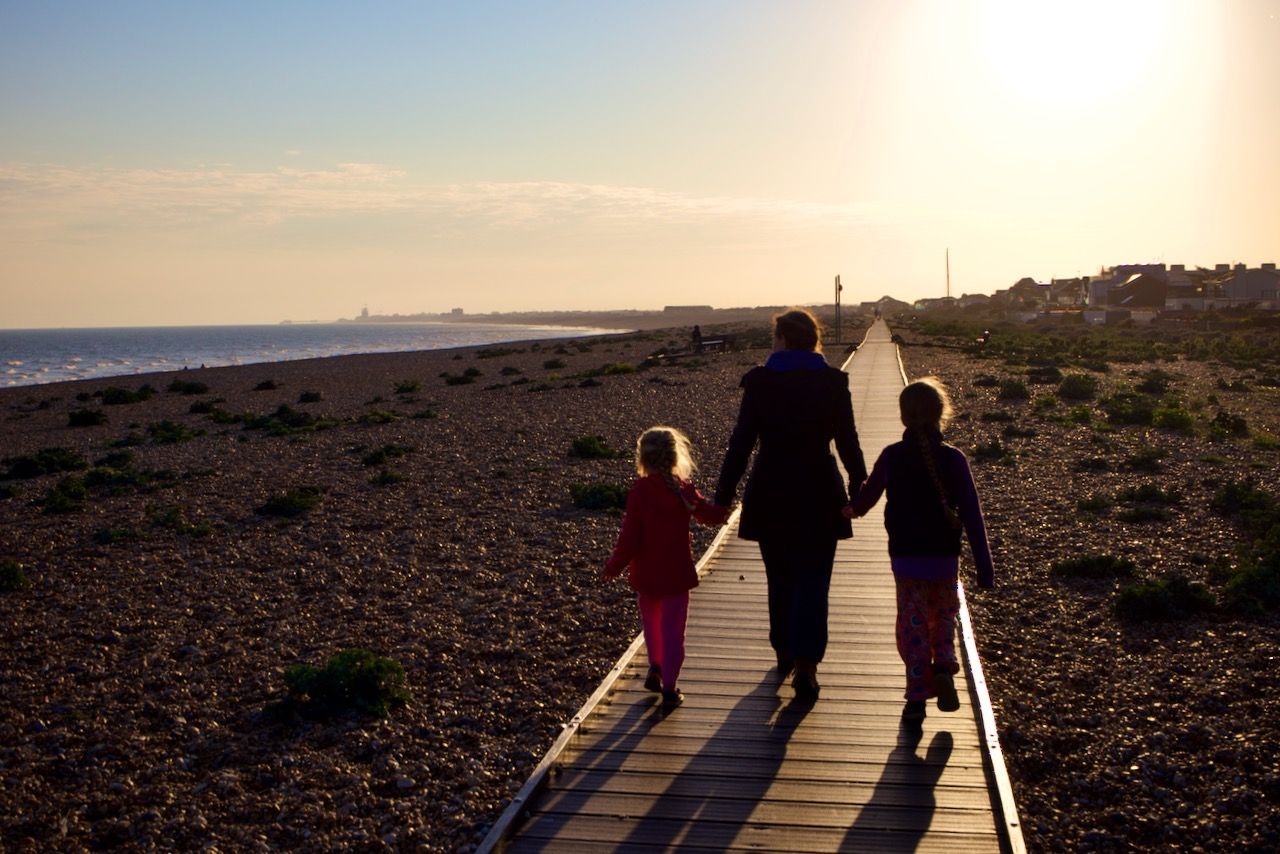 A mother and her children walking on the Shoreham Beach boardwalk near sunset