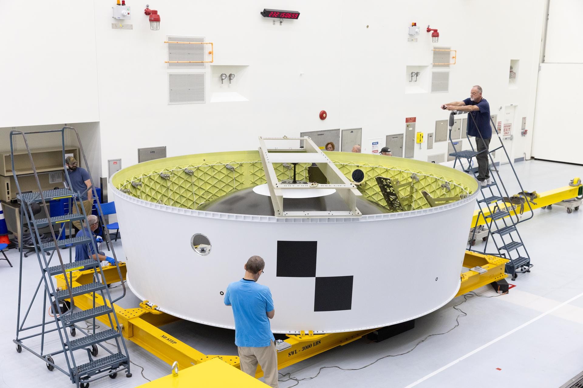 Technicians at the Kennedy Space Center inspect the Orion stage adapter, bound for Artemis II, after its arrival. ยฉKim Shiflett/NASA