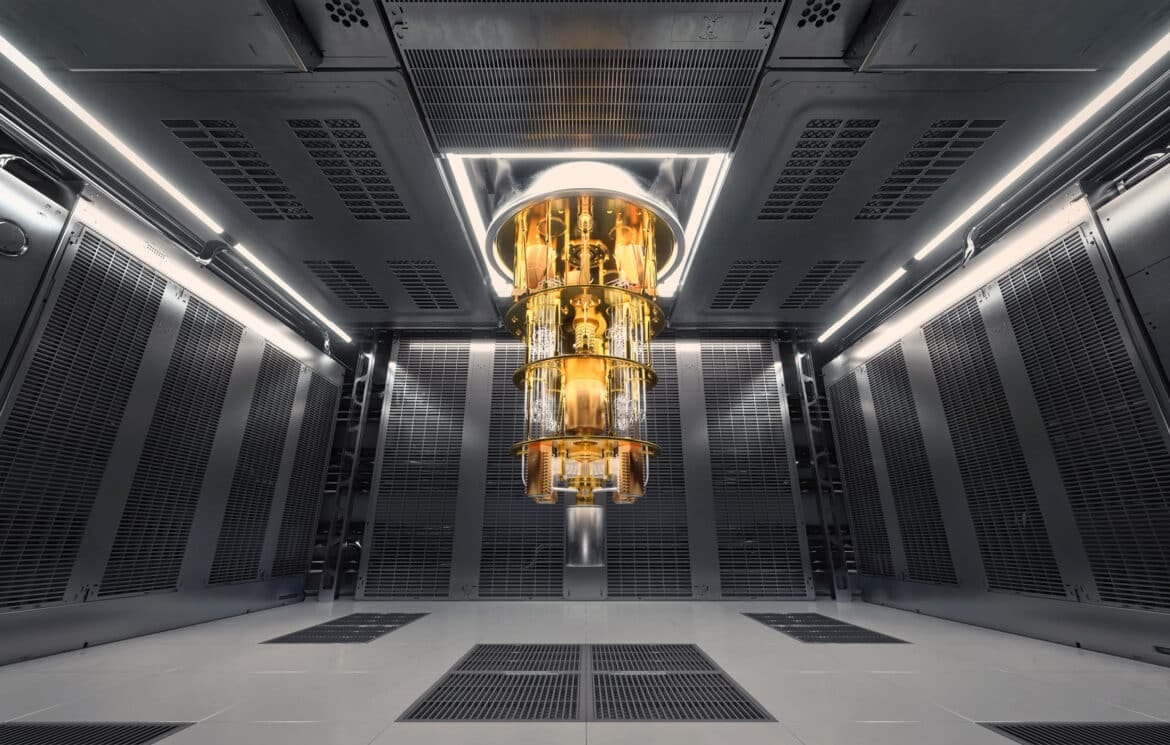 Gold-colored quantum computing hardware inside a large cryogenic cooling chamber surrounded by dark server-like walls and bright industrial lighting.