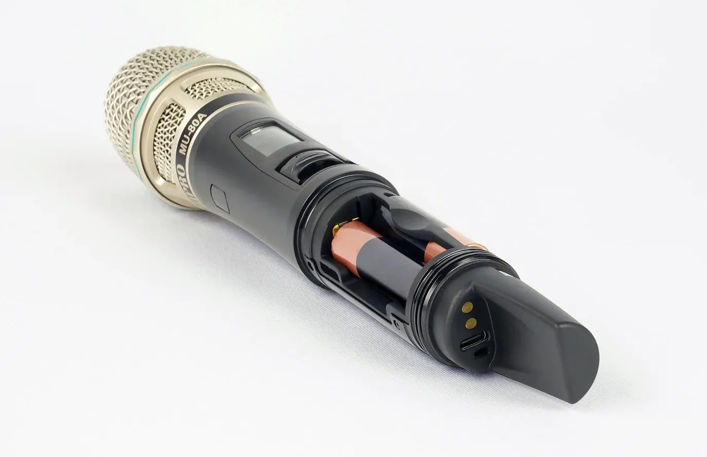 MIPRO ACT-580H 5 GHz 手握式發射器打開電池座，內裝 AA 三號電池，尾端可見兩個金屬充電接點與一個 USB-C 孔
