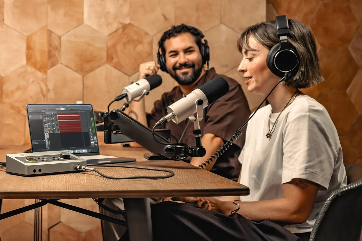兩位主持人戴耳機對著麥克風錄 Podcast，桌上放著 Volt 錄音介面