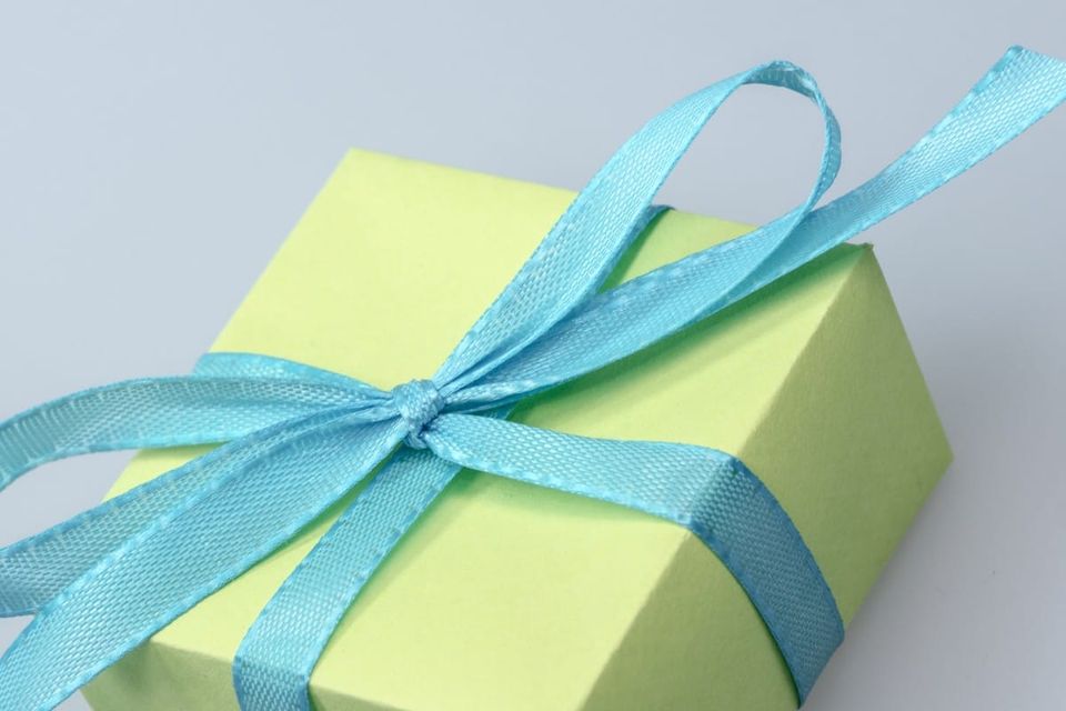 Image: green box wrapped in blue ribbon on grey background