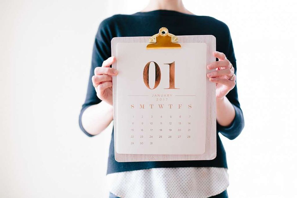Image: Woman holds a calendar on a clipboard.