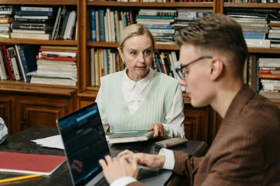 Image: Academic advisor and student share a table in a small office.