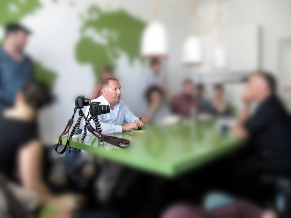 Image: Russell with colleagues at a table, colleagues have been blurred out.