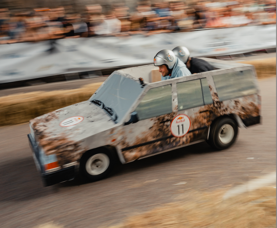 Image: Box car number 11 with two helmeted racers crouching in it.