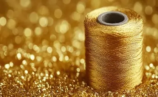Gold metallic yarn spool showing shiny decorative yarn texture