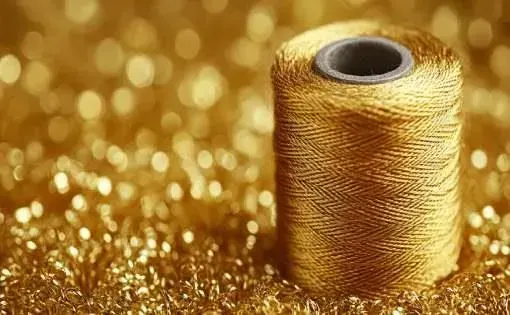 Gold metallic yarn spool showing shiny decorative yarn texture